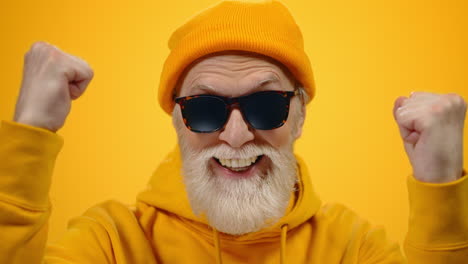 Mature-man-rejoicing-on-studio-background.-Old-cheerful-guy-posing-indoors.