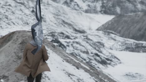 person walking in snowy mountains with a flag