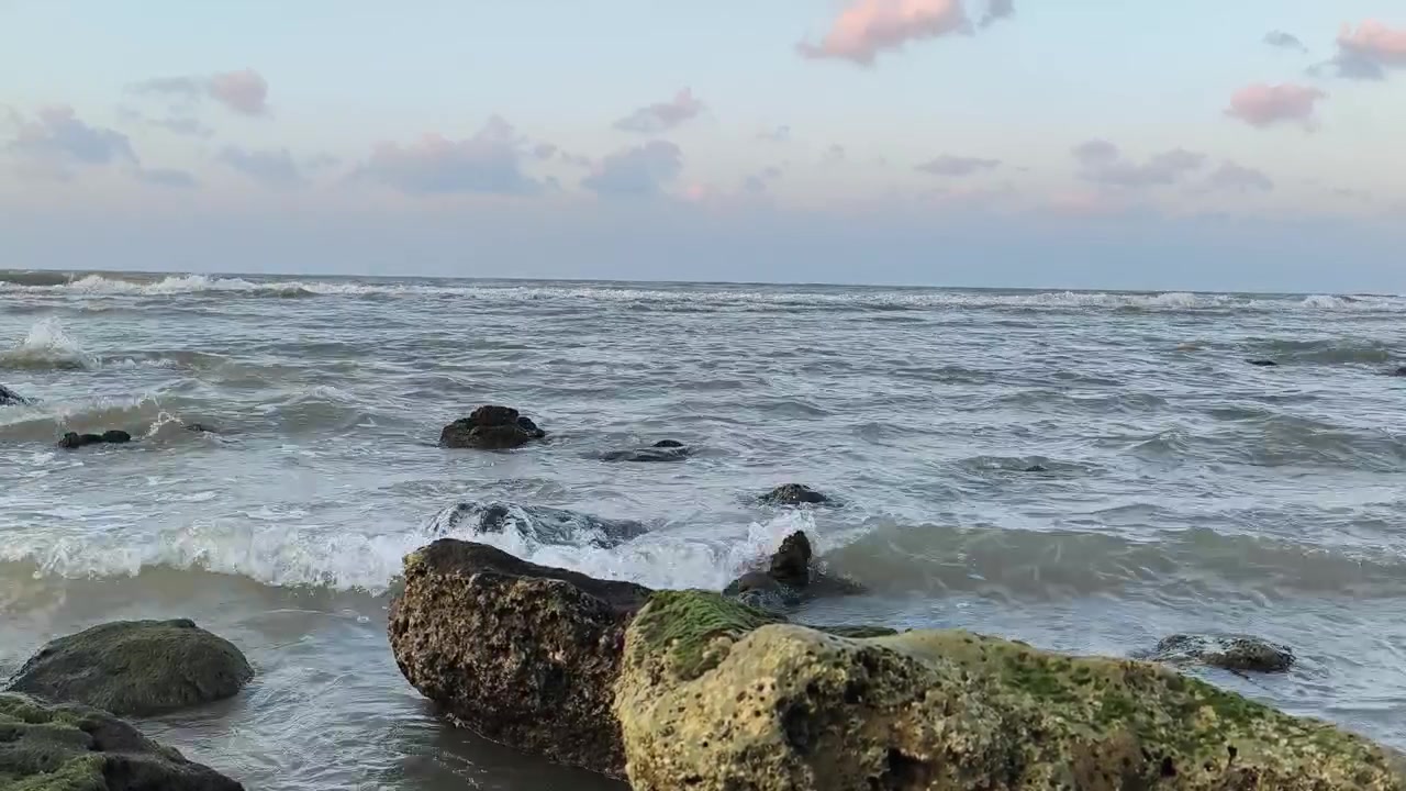 Onde dell'oceano che si infrangono dolcemente contro rocce muschiose al tramonto