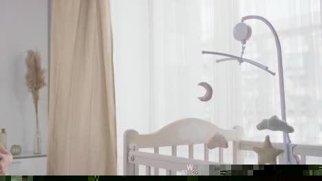 Pregnant-Woman-Approaches-Her-Baby's-Crib-And-Spinning-The-Toy