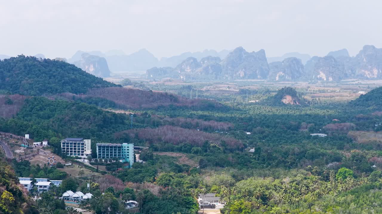 Cảnh quay tĩnh toàn cảnh những vách đá vôi và thảm thực vật rừng rậm xanh tươi dưới bầu trời trong xanh mờ ảo.
