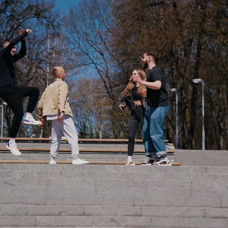 Funny young people dancing outdoors. Group of guys and a girl having joy together in the city park in sunny autumn day. Happy friendship