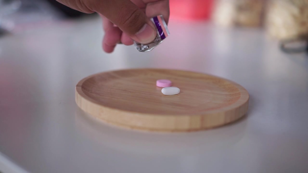 Hand dropping tablet medicine in to a bamboo plate, Suitable for health supplement and vitamin content.