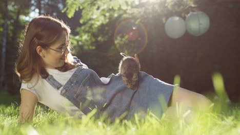 Junge-Kaukasische-Frau,-Die-Auf-Dem-Gras-Liegt-Und-An-Einem-Sommertag-Mit-Einer-Kitty-katze-Im-Park-Spielt