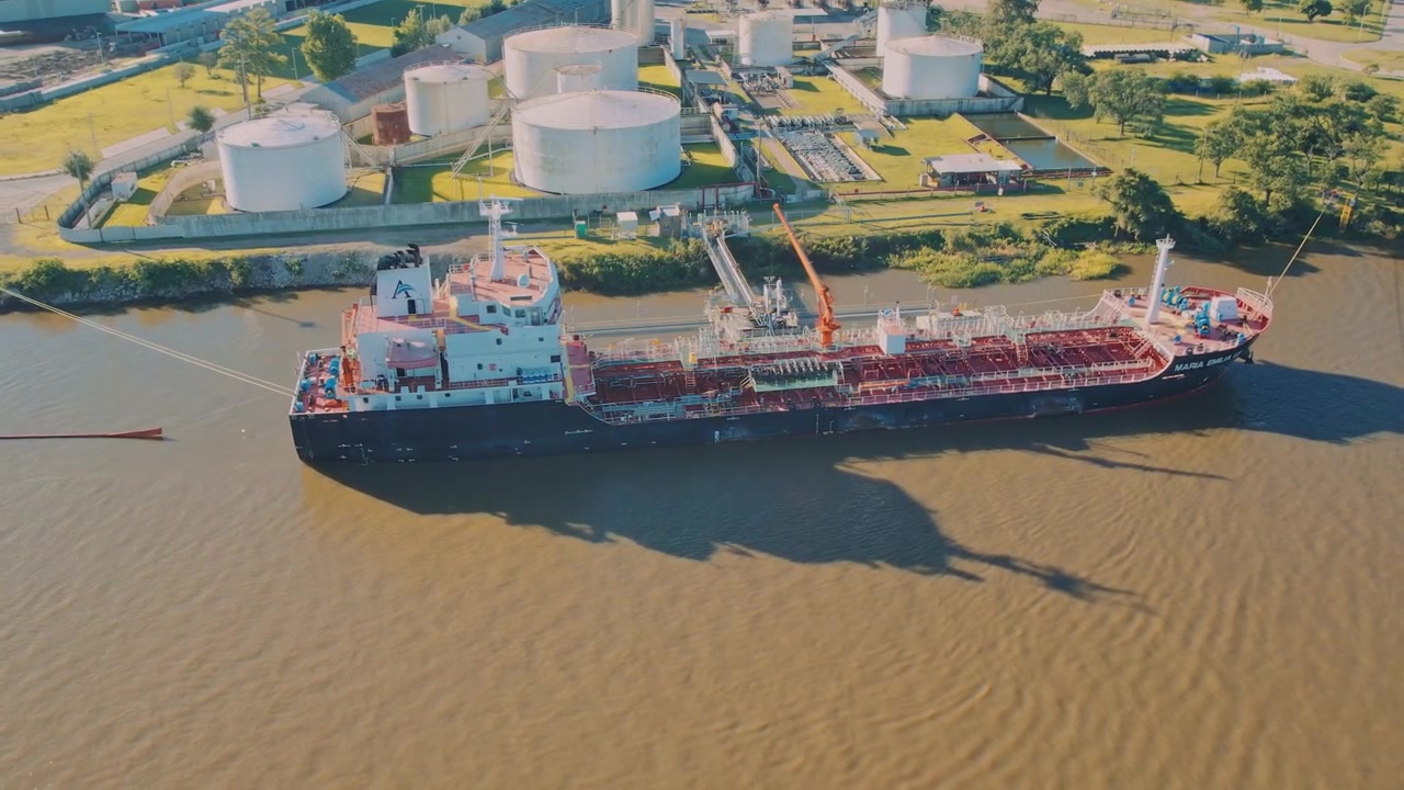 Veduta aerea su un porto petrolifero e una città. Dove una nave sta caricando carburante sul territorio di grandi serbatoi di stoccaggio rotondi per la produzione di carburante industriale in una giornata di sole