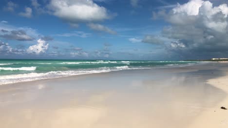 slow motion camera pan along caribbean white sandy beach with cloud formations