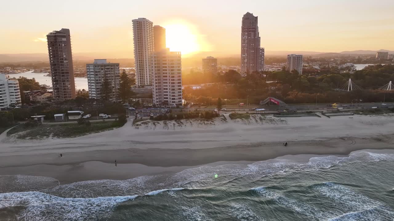 Sunset sun over the high rise buildings at Gold Coast city, Australia. Aerial over the beach.