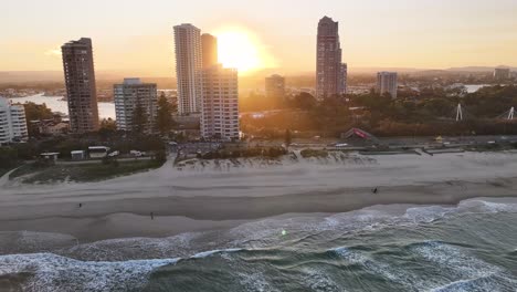 sunset sun over the high rise buildings at gold coast city, australia. aerial over the beach.