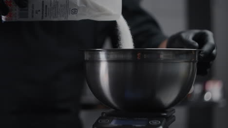 chef adding sugar to mixing bowl