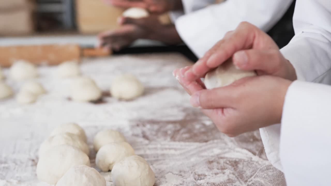 Diverse bakers working in bakery kitchen, making rolls from dough in slow motion