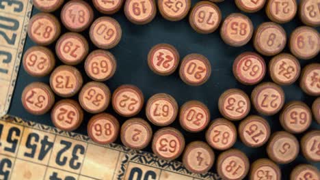 cinematic close-up rotating smooth shot from above of a pile of bingo wooden barrels in a square, woody figures, old numbers background, vintage board game, professional lighting, 4k video