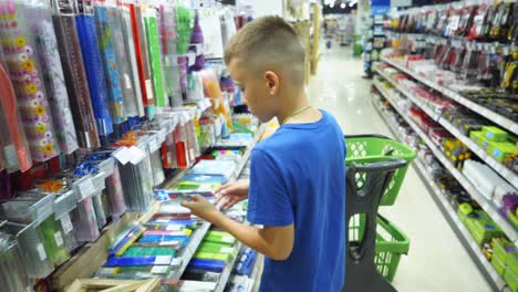 vinnitsa, ukraine - august 20, 2018: boy choosing buying stationery in store preparing for first day in school. back to school concept.