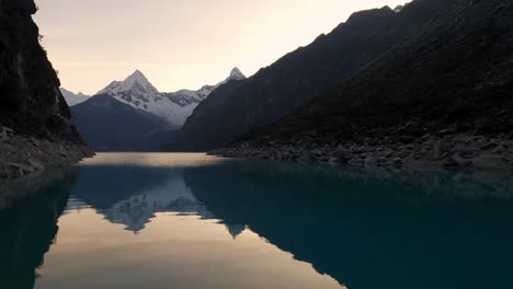 panoramic-of-Lake-Paron,-Pyramid-Mountain-reflection-on-still-water-Andean-Cordillera-in-Peru-Huascaran-National-Park,-Peruvian-Hiking-Destination