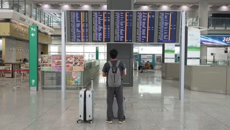 a passenger looks at a flight information screen where airline check-in desks are located in hong kong's international airport