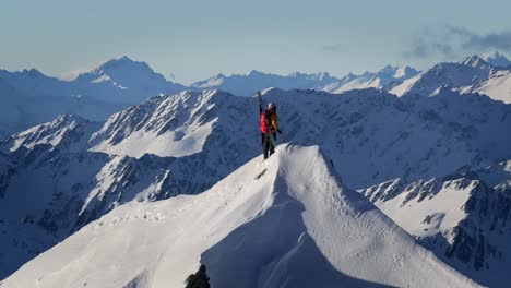 a climber stands atop a snowy mountain in wild nature with huge mountains and giant valleys in the background