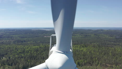 drone pullback pov close to spinning blades of wind turbine in scandinavia