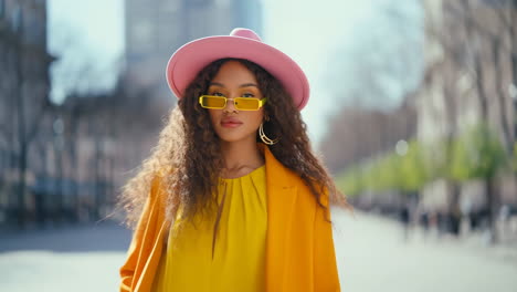 fashionable woman in pink hat and yellow sunglasses on a city street