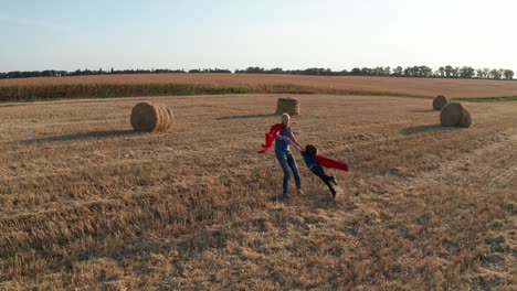 fotografía aérea de un padre dando vueltas alrededor de su hijo sobre un campo de trigo