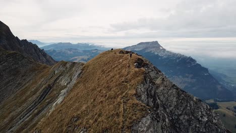 droneshot of 2 hikers in the alpine summits in summer in switzerland 4k