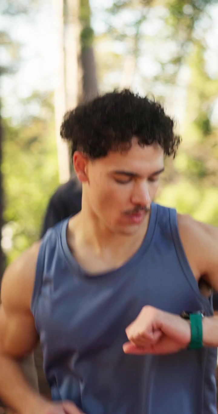 Young Man Jogging Outdoors and Checking His Smartwatch
