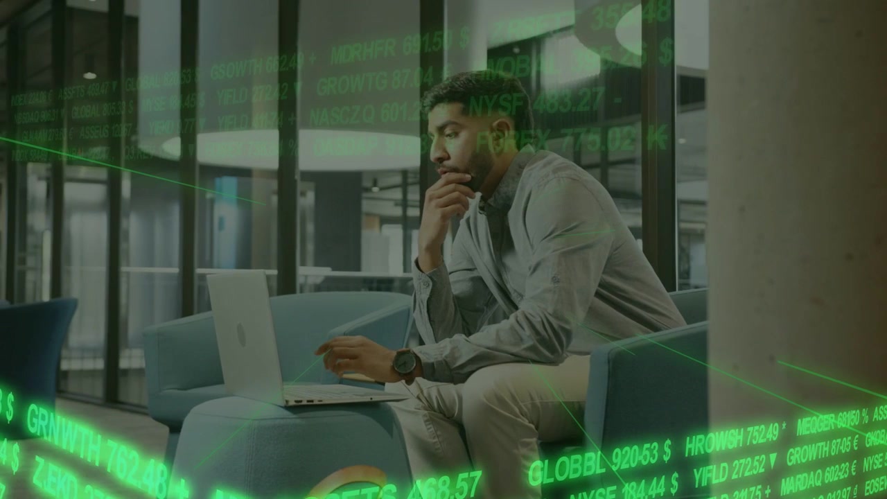 Vertical video: Asian man typing, pausing, resting chin while analyzing laptop with green ticker