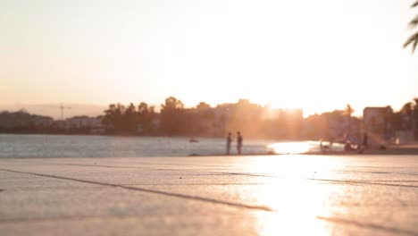 zeitlupe, silhouette eines mannes auf einem rad auf dem bürgersteig am meer während der goldenen stunde