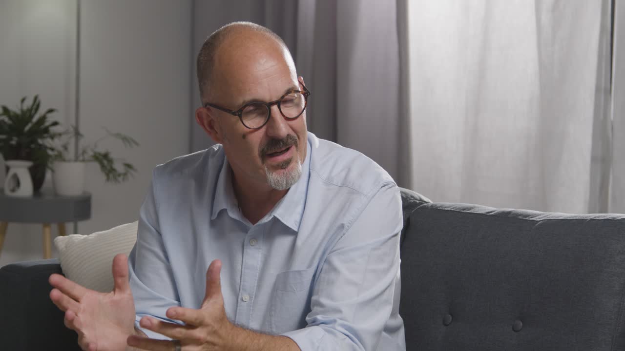 hombre maduro sentado en el sofá hablando con una consejera sobre un problema general o de salud mental 20