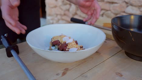 el chef se vuelve y muestra una comida mediterránea con atún crudo y almendras trituradas