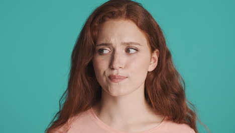 redheaded girl in front of camera on turquoise background.