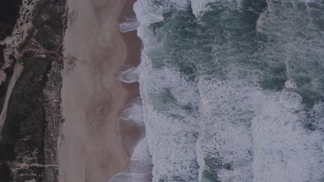 Arriba-Hacia-Abajo-De-Praia-Da-Areeira-Portugal-Con-Pequeñas-Olas-Durante-La-Puesta-De-Sol,-Antena