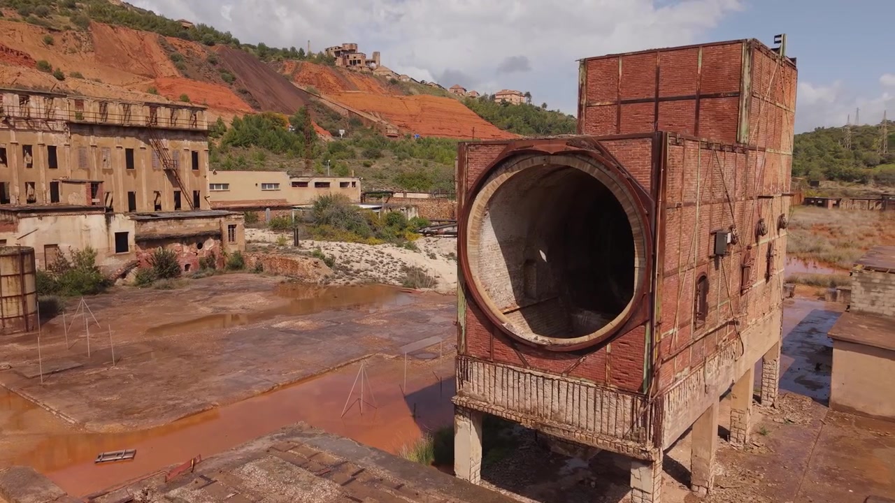 Historic And Rustic Industrial Ruins Of The Abandoned Monteponi Mine Near Iglesias, Sulcis-Iglesiente, Sardinia, Italy. Aerial Shot