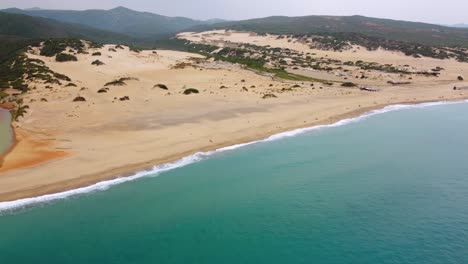 Fliegen-über-Der-Küsteninsel-Sardinien-In-Italien-In-Einer-Natürlichen-Dünenlandschaft-An-Einem-Touristenurlaub-Meeresküste-Sandstrand-Sandige-Bucht-Mit-Klarem-Blauem-Türkisfarbenem-Wasser