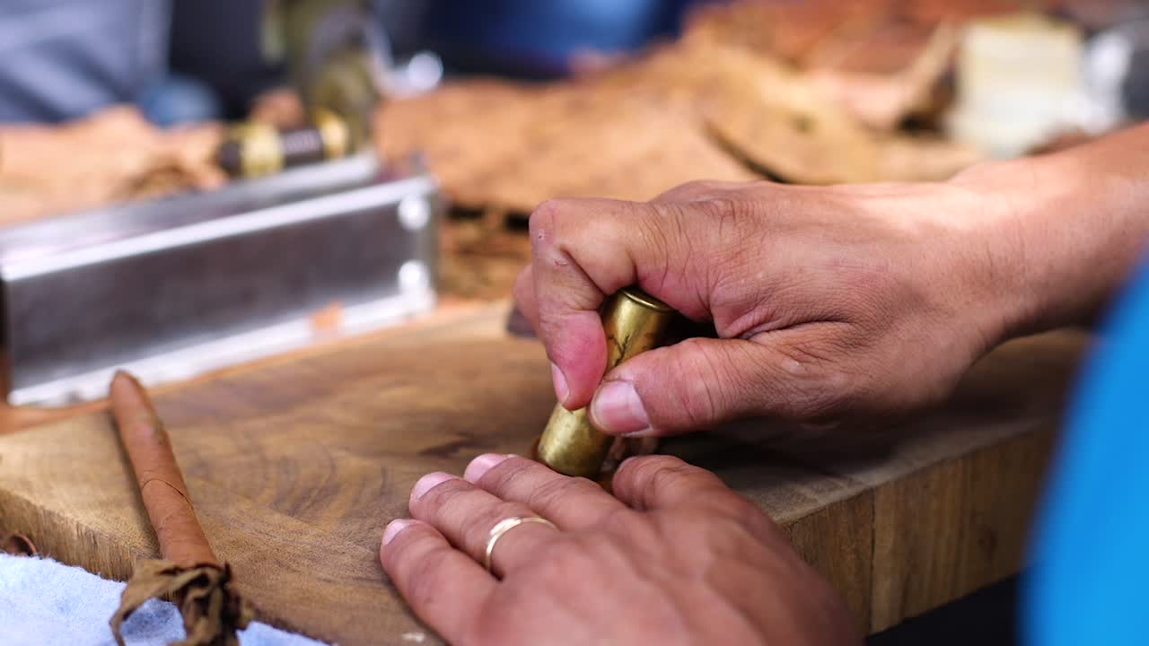 primer plano de manos envejecidas y arrugadas haciendo cuidadosamente un cigarro en el caribe