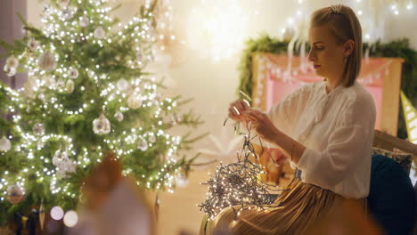 woman in cozy living room untangles christmas lights