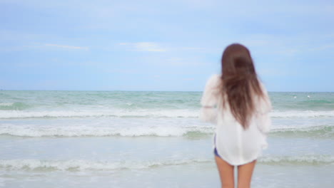 lonesome female running on sand of tropical beach in front of sea waves, slow motion