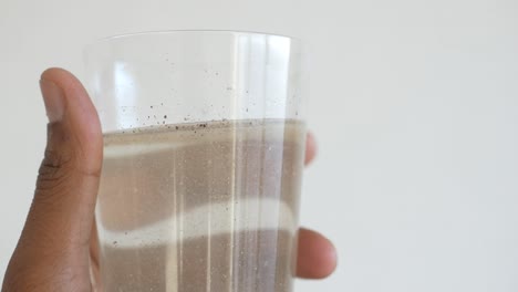 sosteniendo un vaso sucio de agua