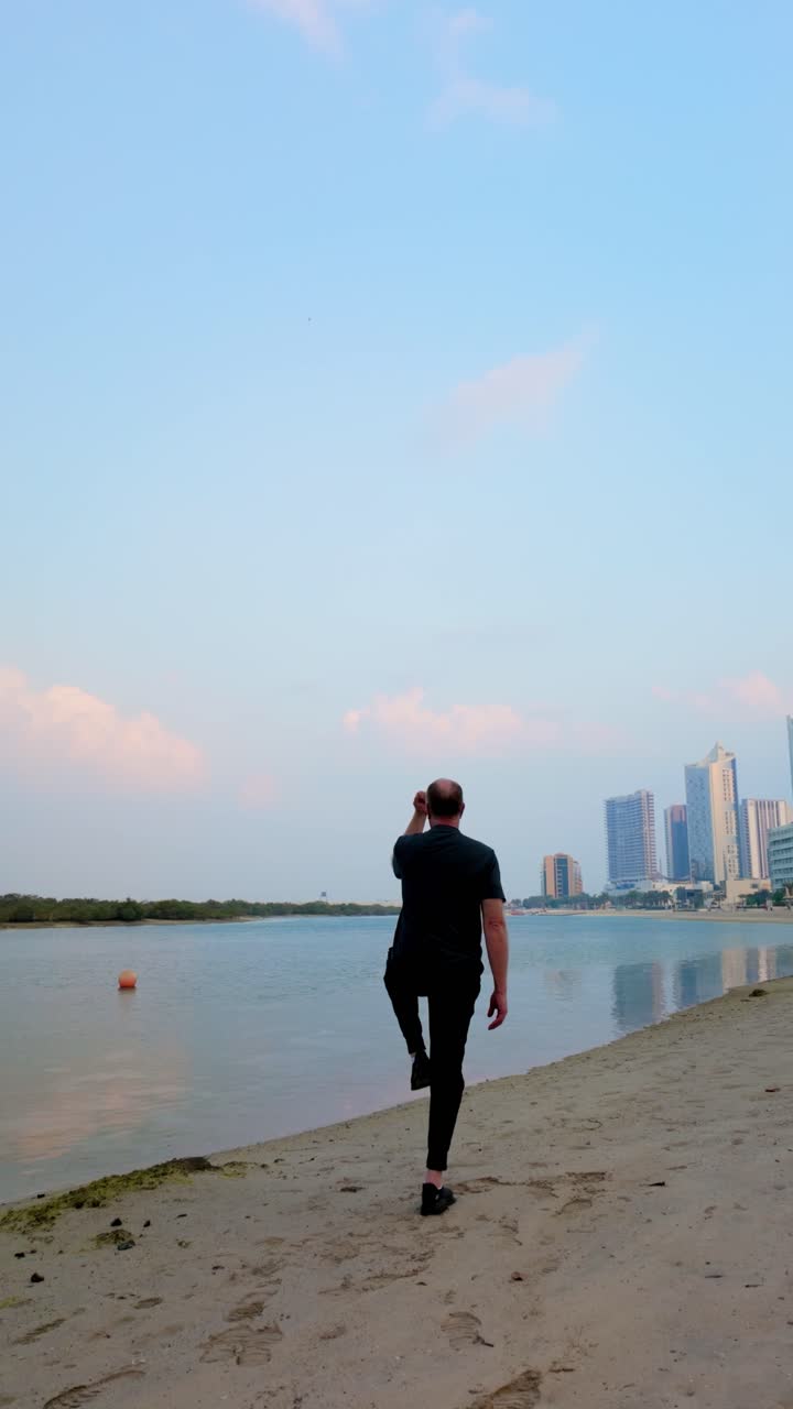Senior Man Doing Tai Chi Yoga Poses For Health And Wellness On An Al Reem Island Beach In Abu Dhabi. Vertical Shot