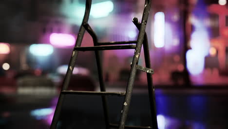 a rusty ladder in front of a neon lit street