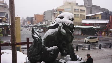 Snow-Falls-over-Guardian-Dog-Statue-in-Kyoto,-Looking-out-from-Gion-Shrine