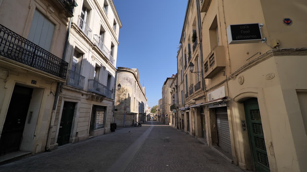 Longue rue vide à Montpellier, pleine de magasins fermés, par une journée ensoleillée en France.