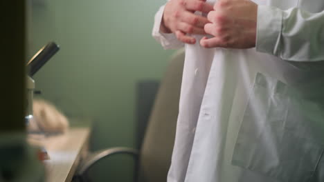 close-up view of a scientist unbuttoning a white lab coat in a laboratory setting