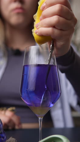 preparing a purple cocktail with lemon juice