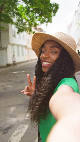 vertical video pov shot of female tourist on vacation in oxford uk exploring city walking along holywell street posing for selfie on mobile phone