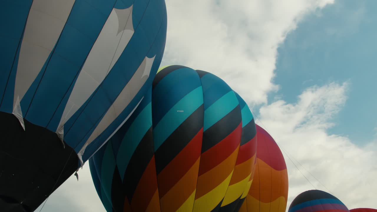 coloridos globos de aire caliente completamente inflados y en fila esperando para despegar del suelo al amanecer o al atardecer con nubes en el fondo