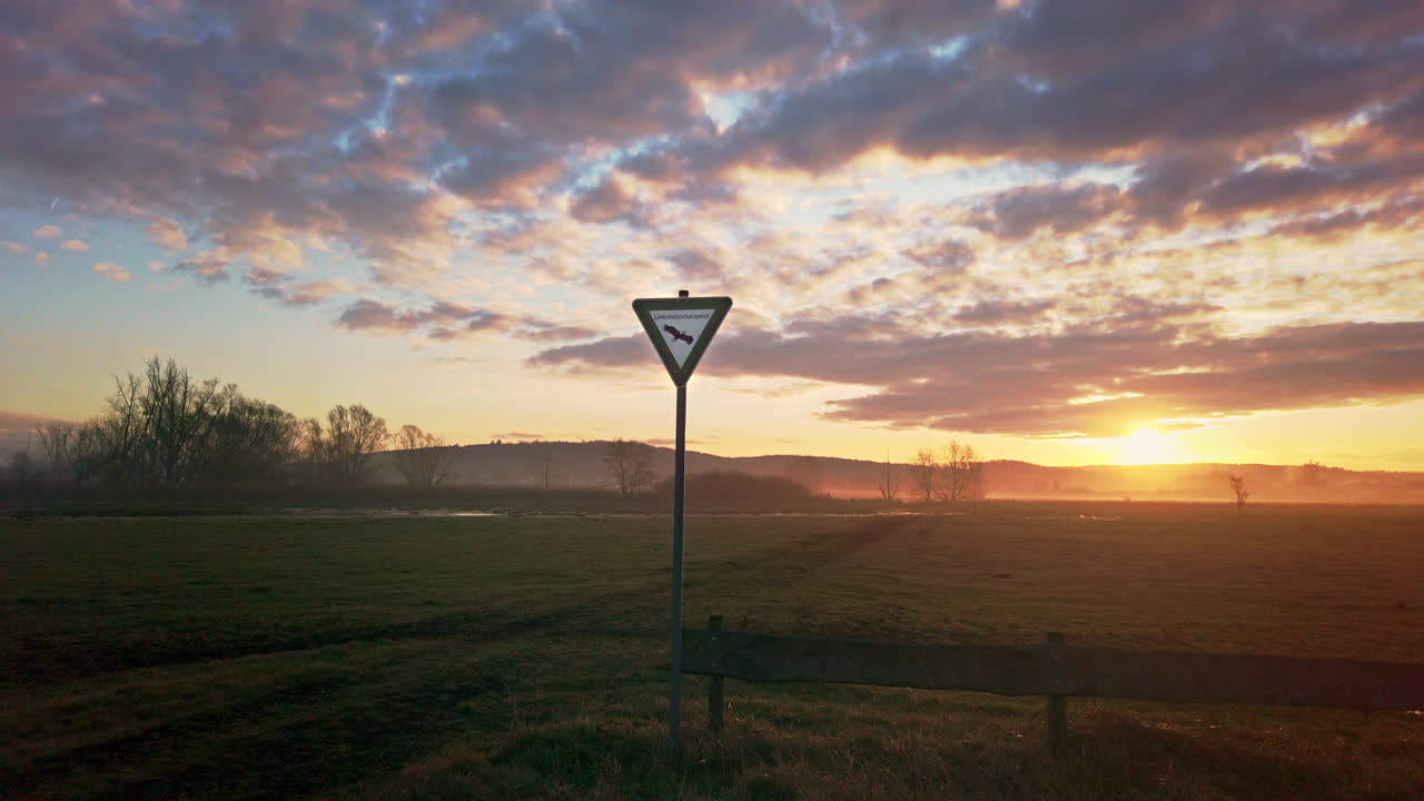 황금빛 일출 동안 아름다운 초원 지역에 있는 독일 자연 보호 구역 표지판의 중간 샷