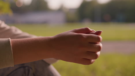 close-up of individual s hands clasped together in a gentle rubbing motion, set against a softly blurred background of green landscape and trees