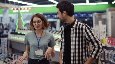 in the electronics store - positive female consultant gives professional advice to a young man. he needs expert opinion. store