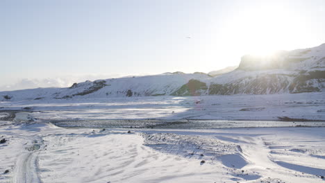 Aerial-shot-of-a-parachuters-silhouette-coming-in-to-land-in-a-snowy-valley-in-Iceland