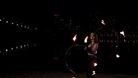 stylish firegirl twisting two fire hoops by hands