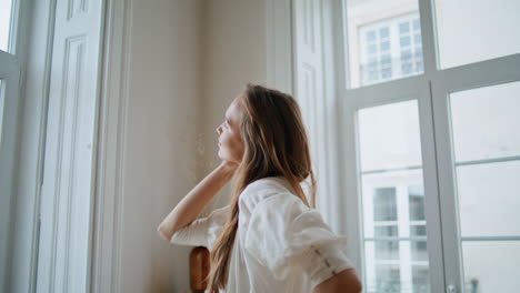 Happy-girl-dancing-at-light-flat-closeup.-Smiling-woman-watching-window-at-home